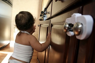 An Infant Reaching for Childproofed Cabinets