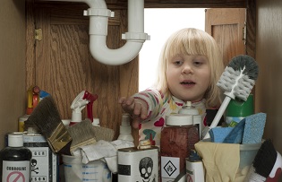 Child Reaching Into a Cabinet of Hazardous Cleaning Products