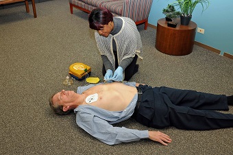 Female demonstrating a first aid on a man in the office
