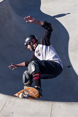 A Skateboarder Equipped with Safety Gear Performs a Move on the Half-Pipe